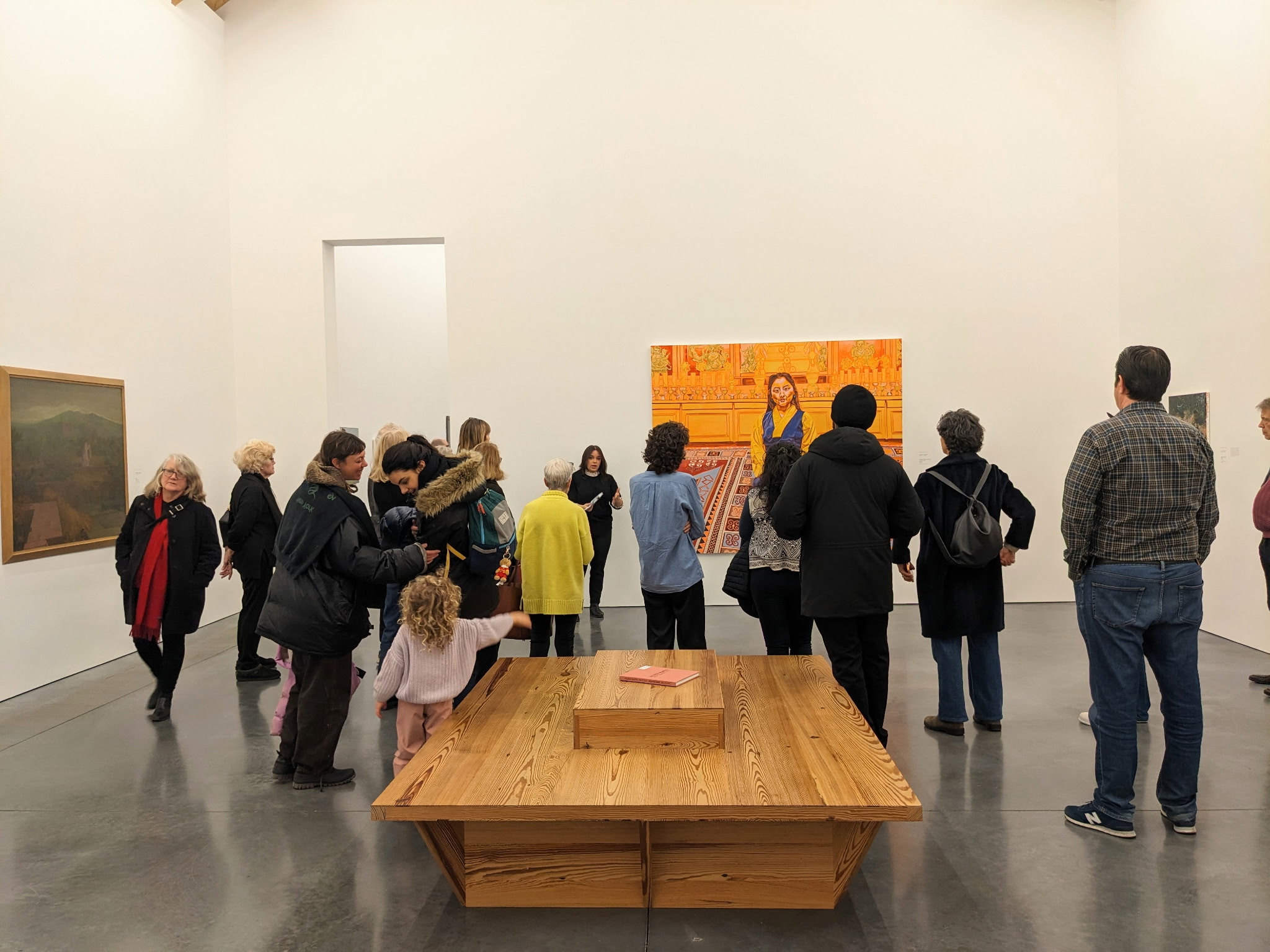 A group of people on a tour in the Museum. A curator is seen among them, leading a tour.